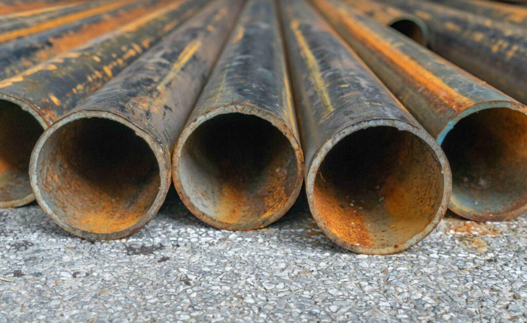 Bull Moose ASTM A 252 rusted construction pipe laid on asphalt